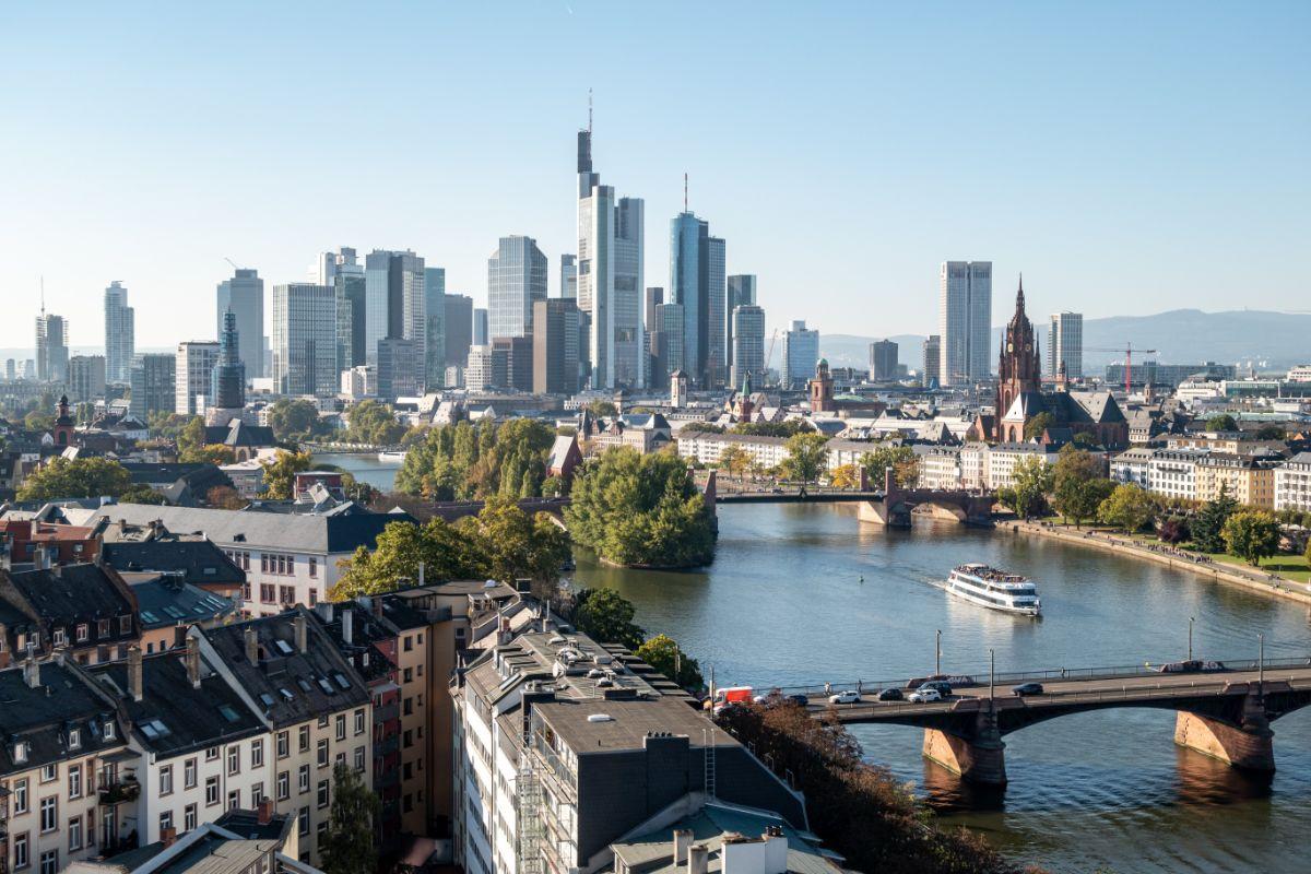 Blick über den Main auf die Frankfurter Skyline mit Hochhäusern, Brücke und Ausflugsschiff