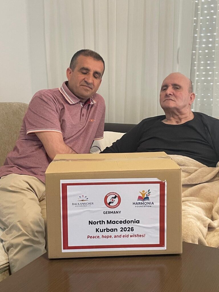 Ein Helfer übergibt ein Kurban-Hilfspaket an einen älteren Mann zu Hause